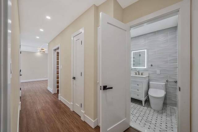 hallway featuring tile walls, sink, and wood-type flooring