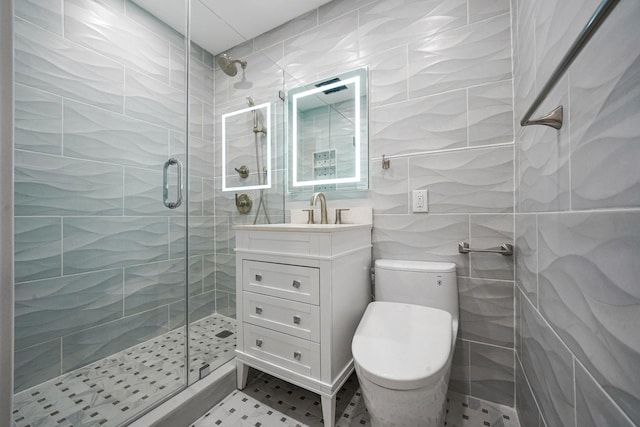 bathroom featuring tile walls, vanity, tasteful backsplash, a shower with shower door, and toilet