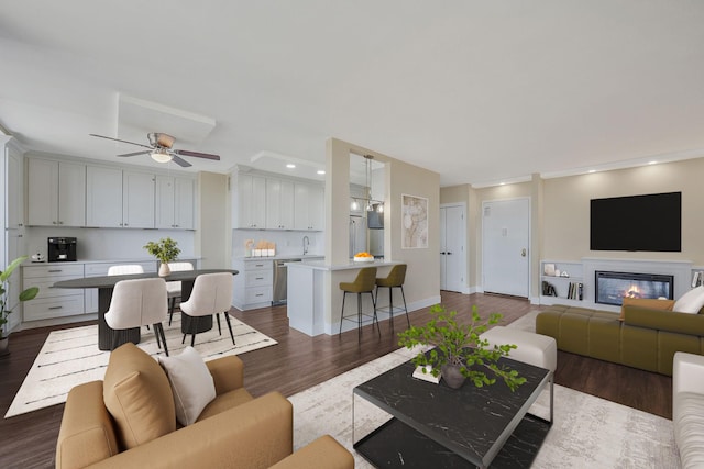 living room with dark wood-type flooring, ceiling fan, and sink