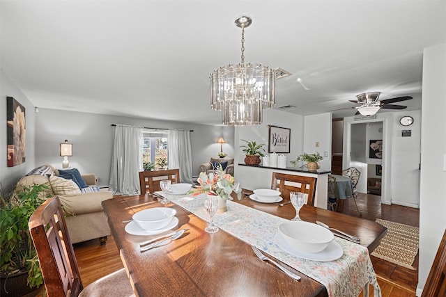 dining room featuring ceiling fan with notable chandelier and hardwood / wood-style floors