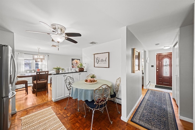 dining space featuring parquet flooring, a baseboard heating unit, and ceiling fan with notable chandelier