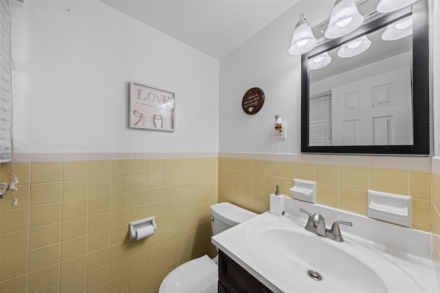 bathroom featuring vanity, toilet, and tile walls