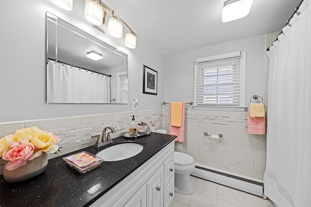 bathroom featuring baseboard heating, vanity, toilet, and tile walls