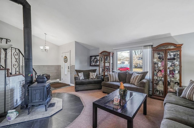 carpeted living room featuring an inviting chandelier, vaulted ceiling, and a wood stove