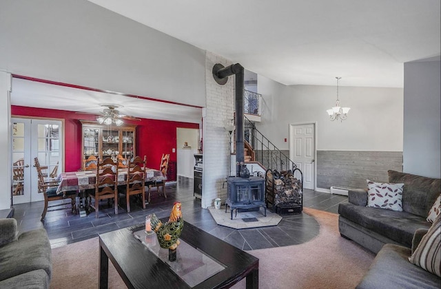 living room featuring french doors, high vaulted ceiling, a wood stove, baseboard heating, and ceiling fan with notable chandelier