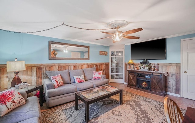 living room with crown molding, tile patterned floors, ceiling fan, and wood walls