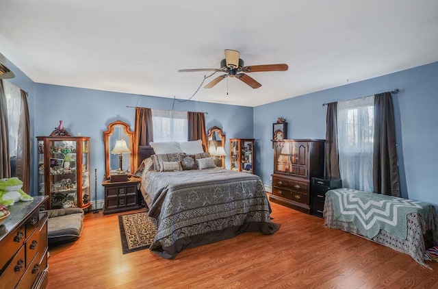 bedroom with ceiling fan, a baseboard radiator, and light hardwood / wood-style flooring