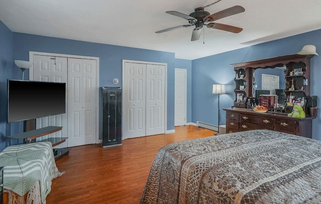 bedroom with multiple closets, a baseboard radiator, ceiling fan, and hardwood / wood-style floors