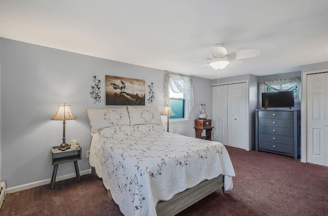 bedroom featuring baseboard heating, ceiling fan, dark carpet, and two closets