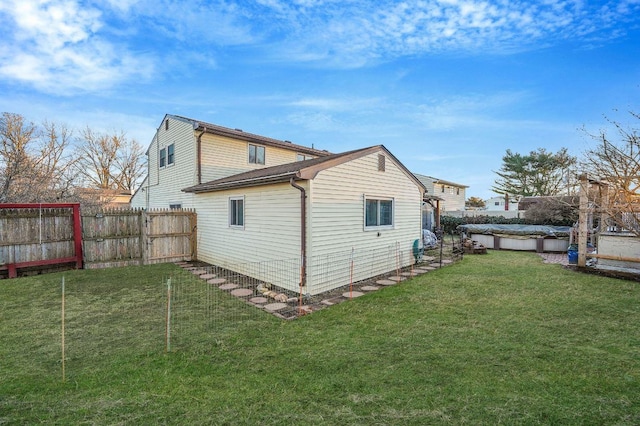 back of house with a covered pool and a lawn