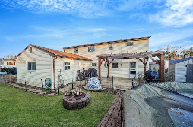 back of property featuring a fire pit, a lawn, a shed, and a pergola