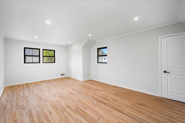 spare room featuring crown molding, a wealth of natural light, and light wood-type flooring