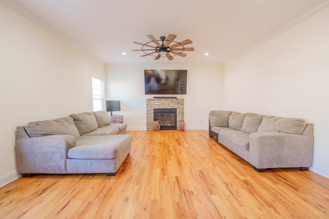 living room with crown molding, a stone fireplace, ceiling fan, and light wood-type flooring