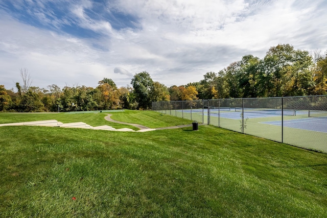 view of tennis court featuring a lawn