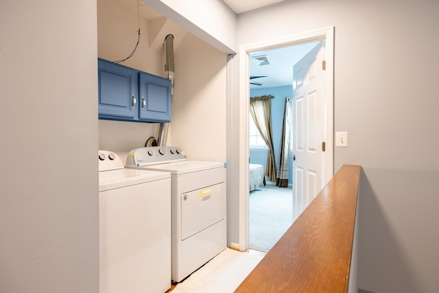 clothes washing area with light carpet, cabinets, and washer and dryer