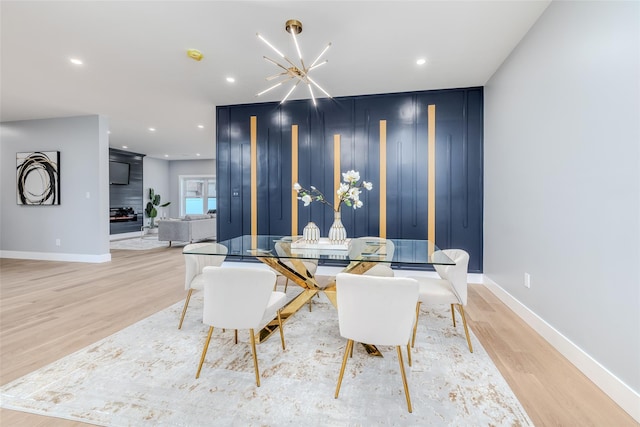 dining room featuring a large fireplace, a notable chandelier, and light hardwood / wood-style flooring