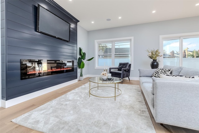 living room with hardwood / wood-style floors, a large fireplace, and a healthy amount of sunlight