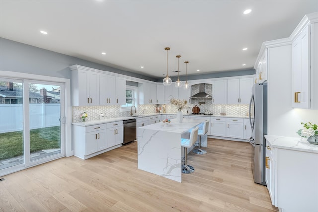 kitchen with wall chimney exhaust hood, white cabinetry, stainless steel appliances, and a kitchen island