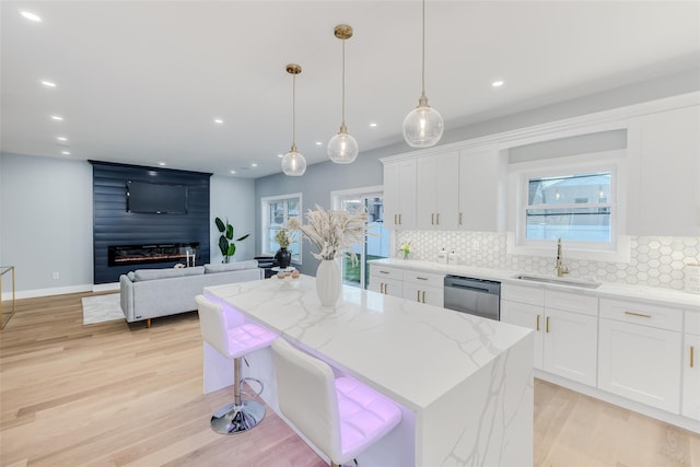 kitchen featuring a kitchen island, decorative light fixtures, sink, white cabinets, and stainless steel dishwasher