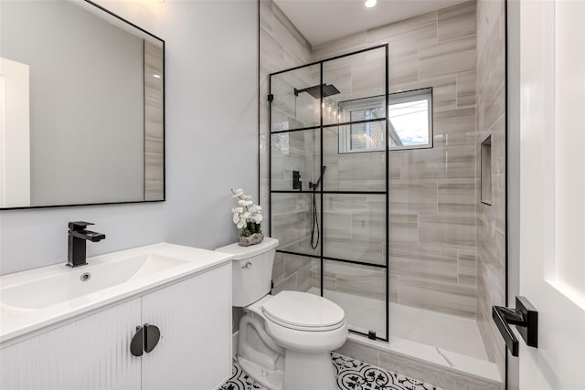 bathroom with vanity, tiled shower, and toilet