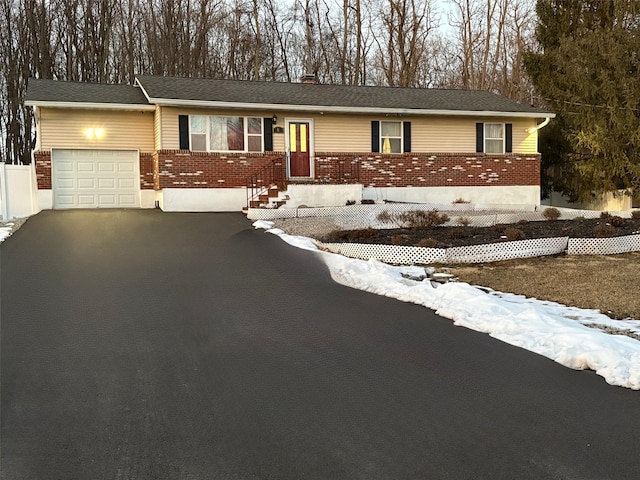 ranch-style house with a garage, driveway, and brick siding