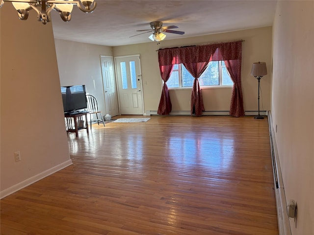 unfurnished living room with baseboards, light wood finished floors, and ceiling fan with notable chandelier