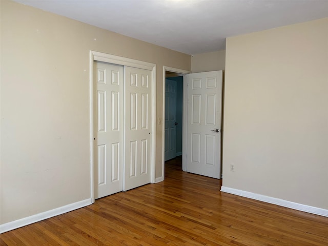 unfurnished bedroom with a closet, wood finished floors, and baseboards