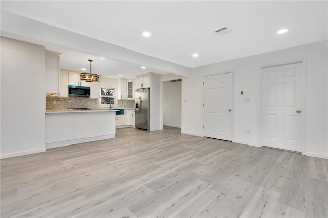 kitchen featuring hanging light fixtures, white cabinetry, stainless steel refrigerator with ice dispenser, and decorative backsplash