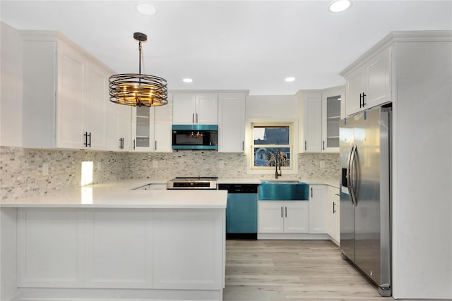 kitchen featuring hanging light fixtures, appliances with stainless steel finishes, white cabinets, and kitchen peninsula