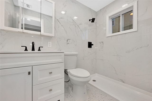 bathroom featuring vanity, tile walls, toilet, and a tile shower