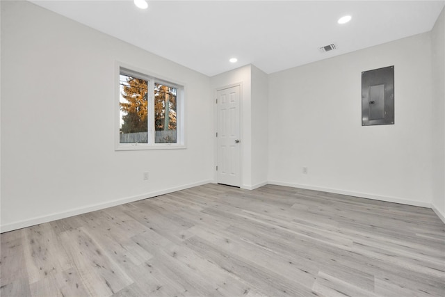 spare room featuring electric panel and light hardwood / wood-style flooring