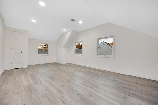 additional living space featuring vaulted ceiling and light hardwood / wood-style flooring