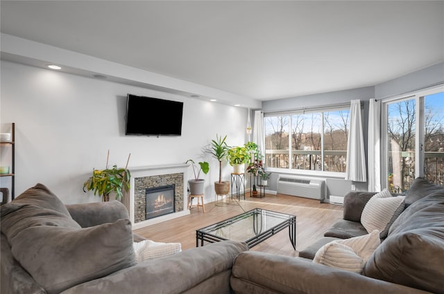 living room featuring a wall mounted air conditioner, a fireplace, and light hardwood / wood-style floors