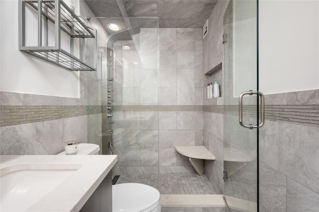 bathroom with vanity, toilet, a shower with door, and tile walls