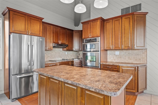 kitchen featuring tasteful backsplash, hanging light fixtures, a kitchen island, and appliances with stainless steel finishes