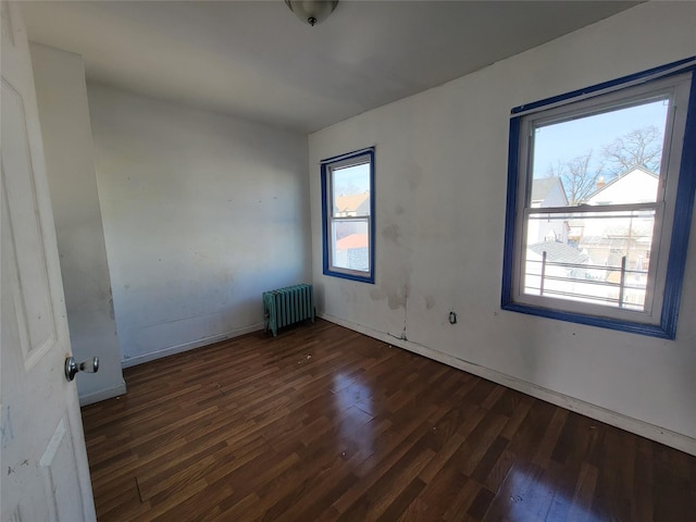 spare room featuring radiator and dark hardwood / wood-style floors