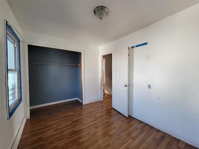 unfurnished bedroom featuring a baseboard radiator, dark hardwood / wood-style flooring, and a closet