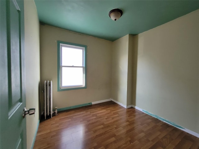 empty room featuring radiator heating unit and dark hardwood / wood-style flooring