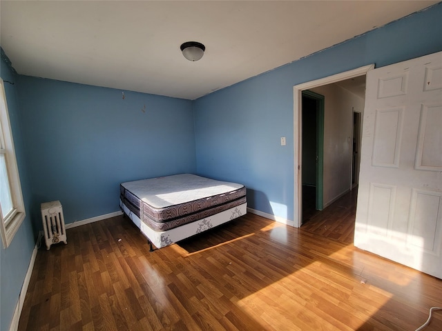 unfurnished bedroom featuring hardwood / wood-style flooring and radiator heating unit