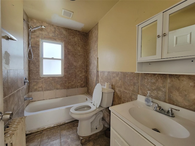 full bathroom featuring tile walls, tiled shower / bath combo, vanity, toilet, and tile patterned floors