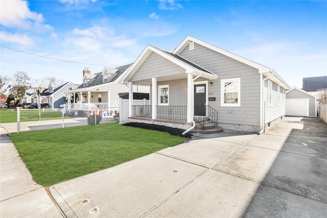 view of front facade with a garage, an outbuilding, covered porch, and a front lawn