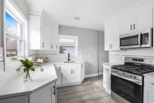 kitchen featuring appliances with stainless steel finishes, sink, white cabinets, and light hardwood / wood-style floors