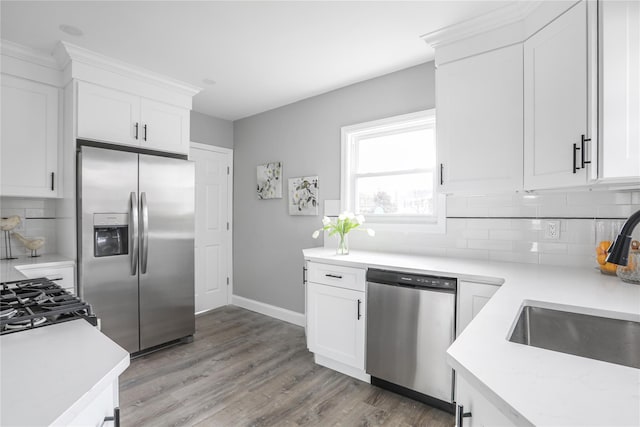 kitchen featuring appliances with stainless steel finishes, sink, white cabinets, and light wood-type flooring