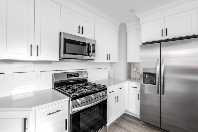 kitchen with crown molding, appliances with stainless steel finishes, white cabinets, decorative backsplash, and light wood-type flooring