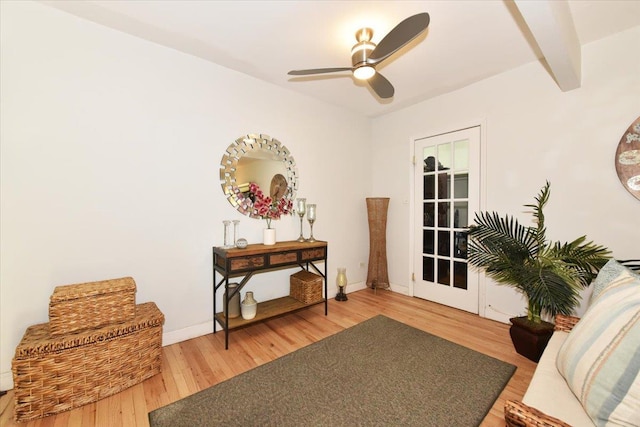 living area featuring hardwood / wood-style flooring, ceiling fan, and beamed ceiling