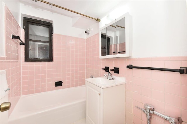 bathroom featuring vanity, tiled shower / bath combo, and tile walls