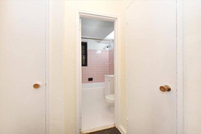 bathroom featuring tile patterned floors, toilet, and a tile shower