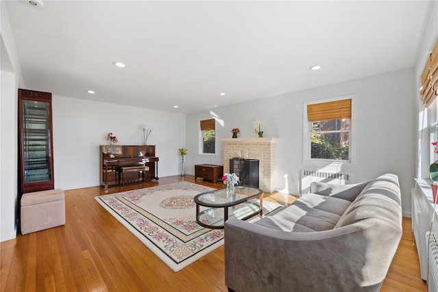 living room with radiator, a fireplace, and light hardwood / wood-style floors