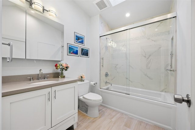 full bathroom featuring hardwood / wood-style flooring, vanity, bath / shower combo with glass door, and toilet