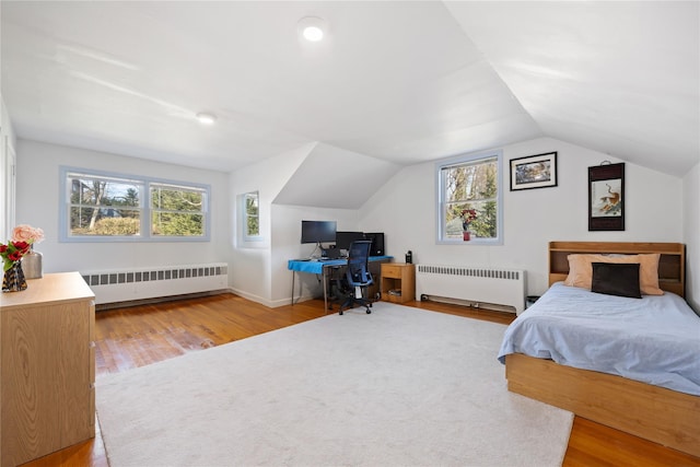 bedroom with lofted ceiling, radiator, and light wood-type flooring